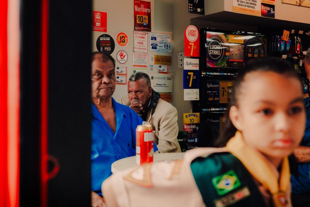 Interior de loja brasileira com pessoas e anúncios de tabaco, fotografia de Alexandre de Olanda