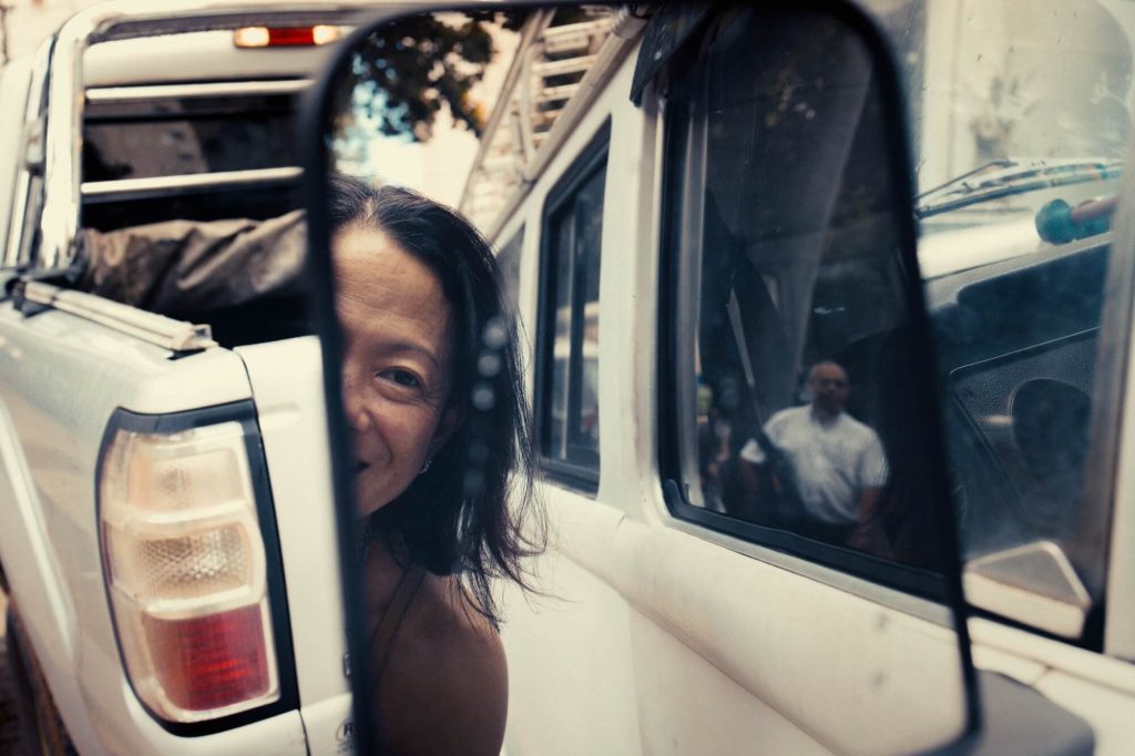 Pessoa parcialmente visível atrás de caminhonete branca, fotografia de Alexandre de Olanda