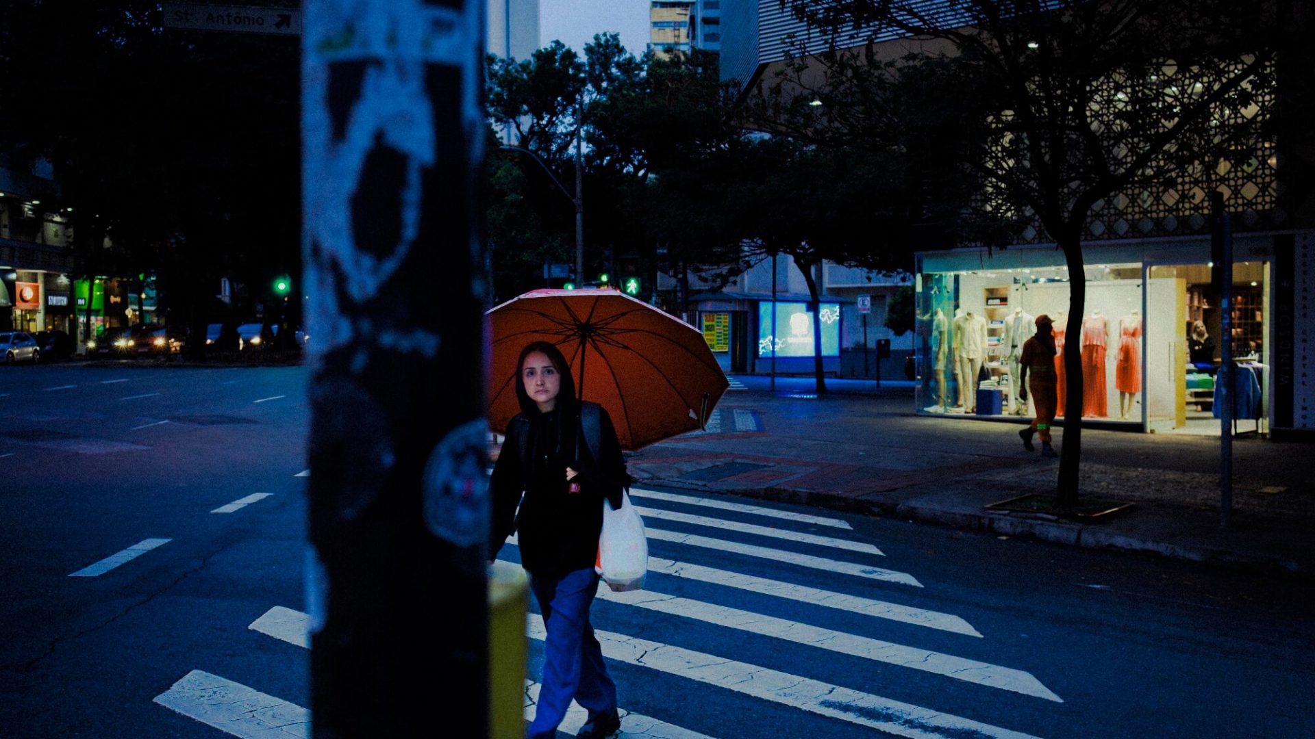 Pessoa atravessando rua com guarda-chuva laranja, fotografia de Alexandre de Olanda